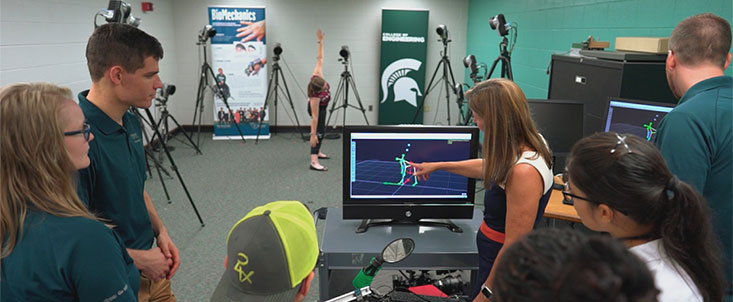 Doctor Tammy Reid Bush and students look at a computer together. 
