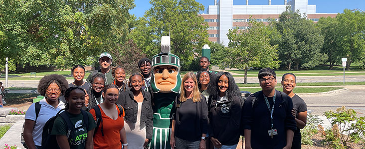 Group photo-op outside with mascot Sparty