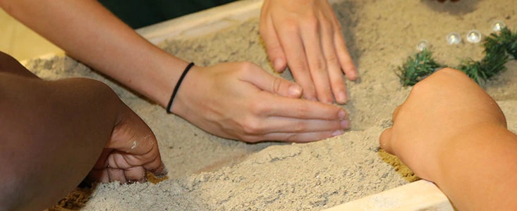 close up of a diverse color of hands working in a sand box during a k-12 wie event
