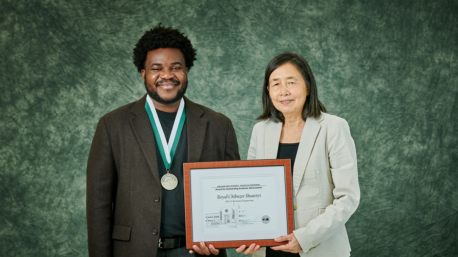 graduate student and professor smiling and holding plaque