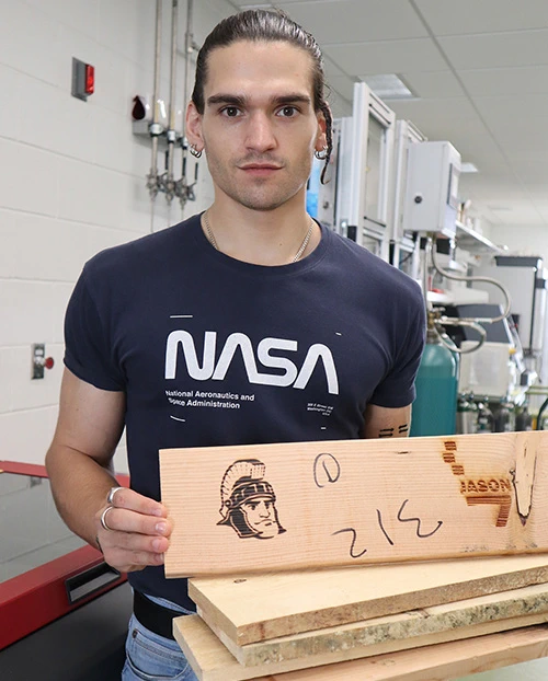 Vittorio Mottini, a biomedical engineering doctoral student in Jinxing Li’s lab at MSU, holds a stack of samples the team is using in their new “living wood” project. The team laser etched an image of Sparty, MSU’s mascot, in the top plank. Credit: Jinxing Li