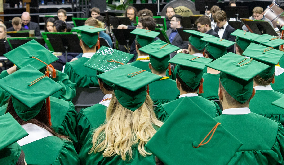 A sea of students in their cap and gown, with their back facing the viewer