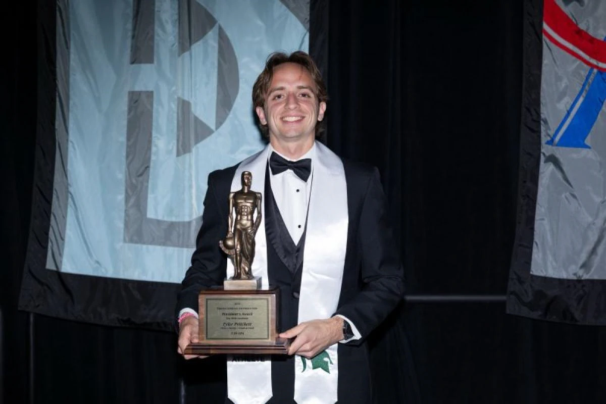 Tyler Pritchett in a tuxedo holding an award