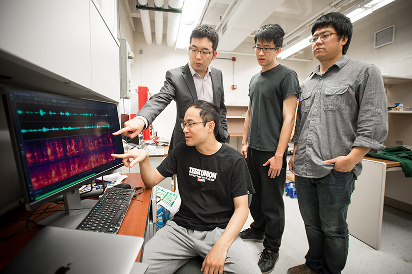 Mi Zhang (left, standing) and his team - which includes doctoral student Xiao Zeng (seated), research associate Kai Cao (right, standing) and undergraduate student Haochen Sun (center, standing) - are working on developing a smart hearing aid device that can enhance the clarity of conversation and remove unwanted sounds in the background.