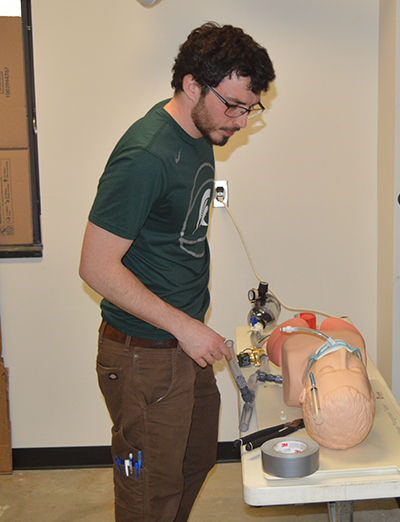 PhD student Joseph Kerwin works on the MSU model ventilator.