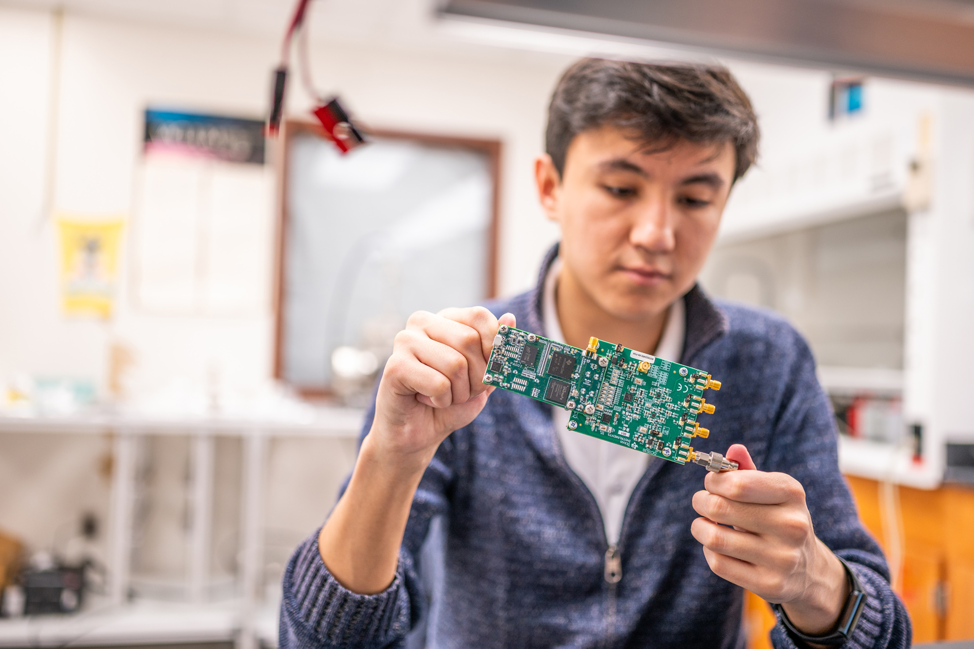 Dimash Aimurzayev, a master’s student in electrical engineering at MSU, examines a circuit board. Electronics like this will be tested at the new Space Electronics Center. Credit: Derrick L. Turner