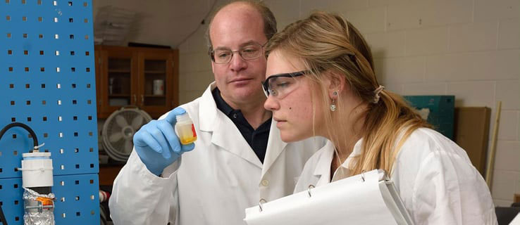 Two people analyzing a vial