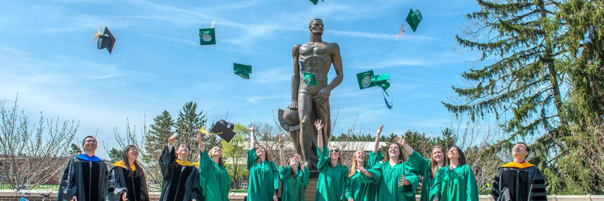 Spartan Engineering graduates celebrate near the Spartan statue.