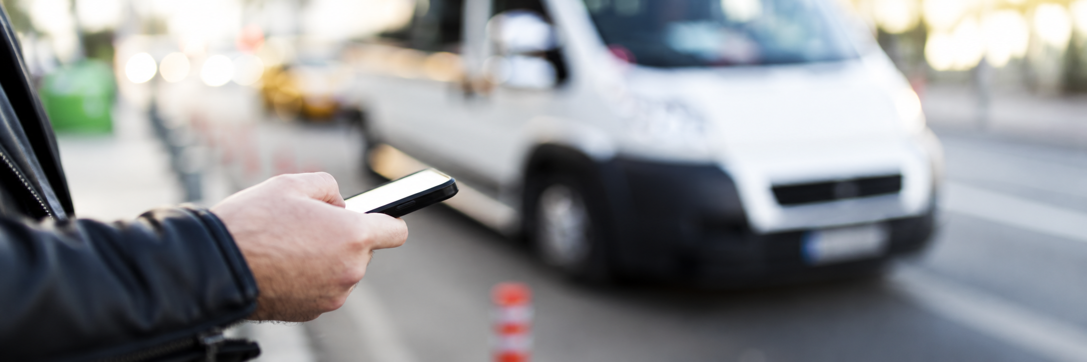 Person holding smart phone in front of vehicle