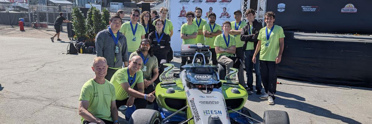 PoliMOVE-TEC team members gather with Minerva and the team’s second- and third-place trophies following the Indy Autonomous Challenge at WeatherTech Raceway Laguna Seca