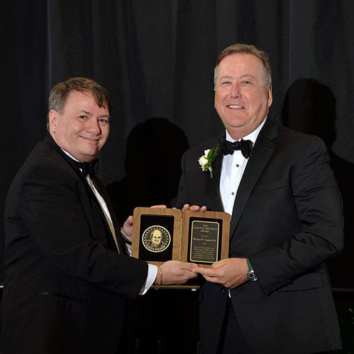 Michael W. Lamach Sr. accepting the 2022 Alumni Award from Dean Kempel