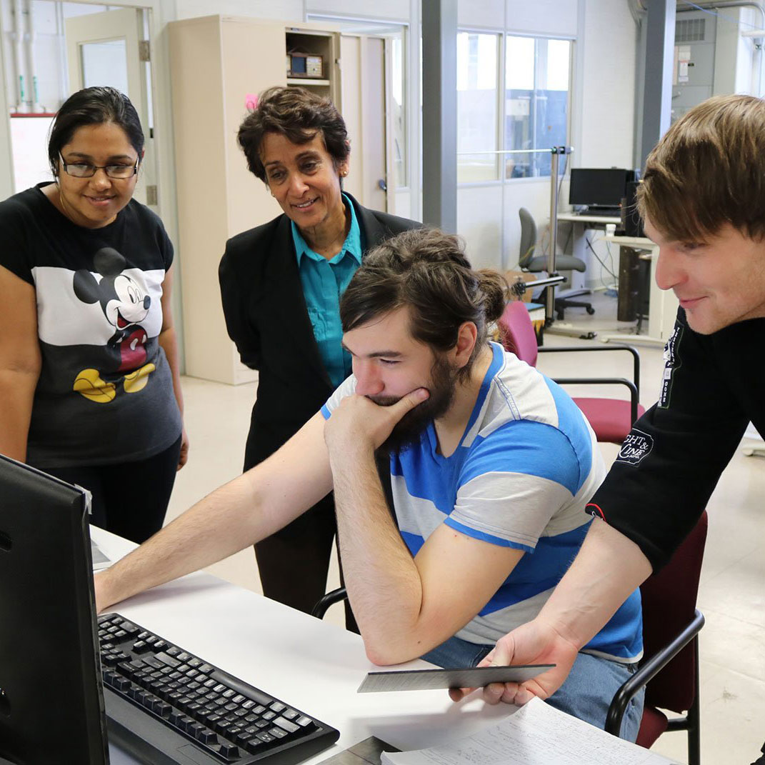 Students and professor gathered around a computer