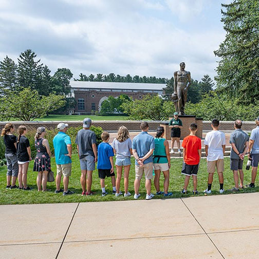 Individuals participating in a Campus Tour in front of the Spartan Statue