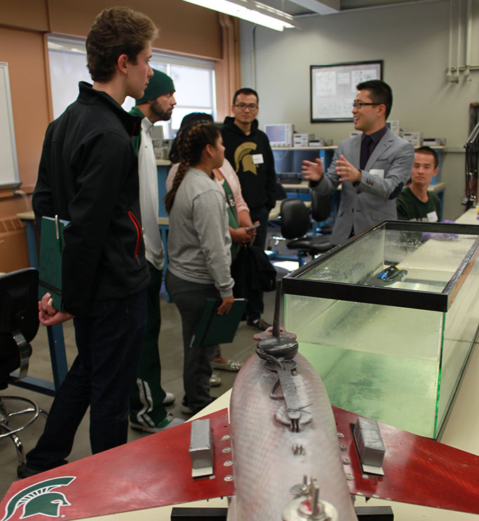 Individual presenting to students with a mechanical plane in the foreground