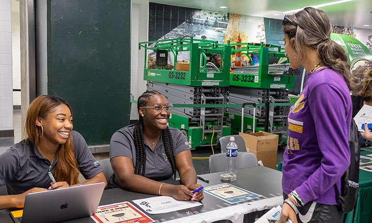 Undergraduate students at a booth talking to a student about their student group