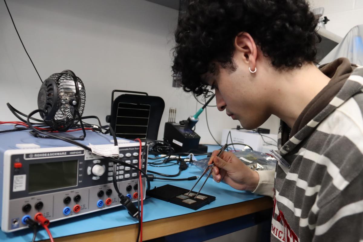 Person holding forceps looking at a piece of equipment