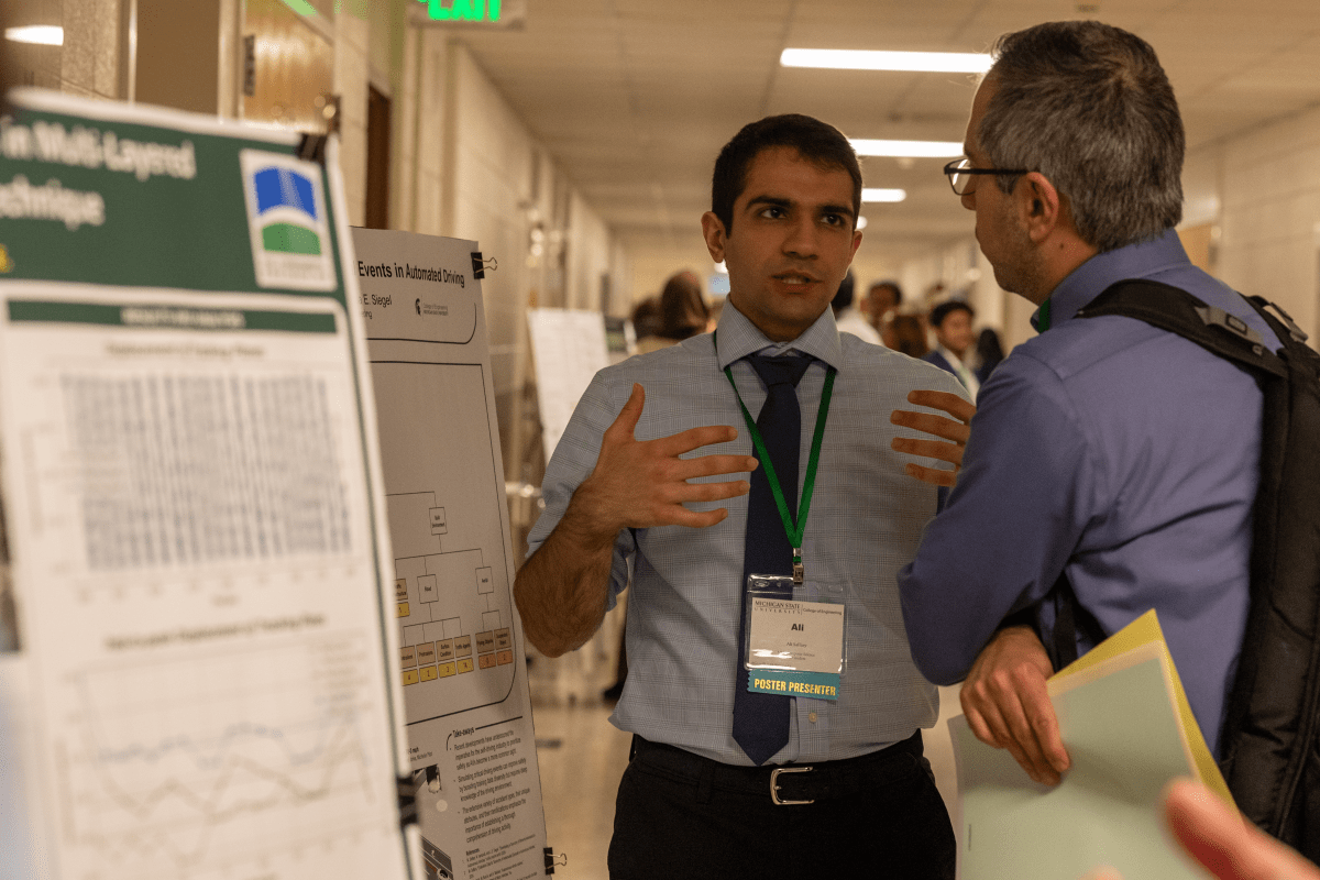 A student presenting their poster to another person